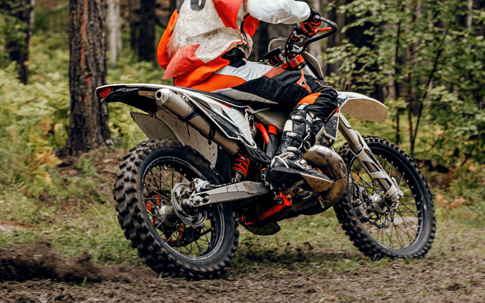 Motocross rider on dirt bike in a forest trail, navigating a forest path.