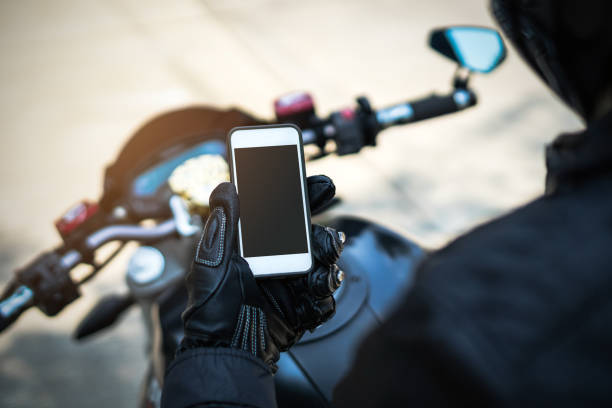 Motorcyclist wearing black attire, using a smartphone,