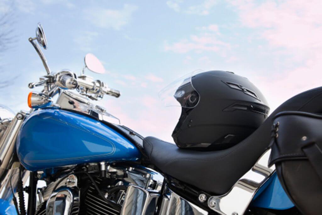 A close-up of a glossy blue motorcycle with a black helmet placed on the seat