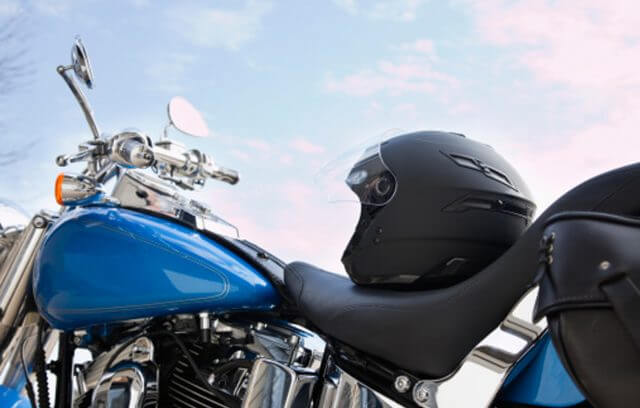 A close-up of a glossy blue motorcycle with a black helmet placed on the seat
