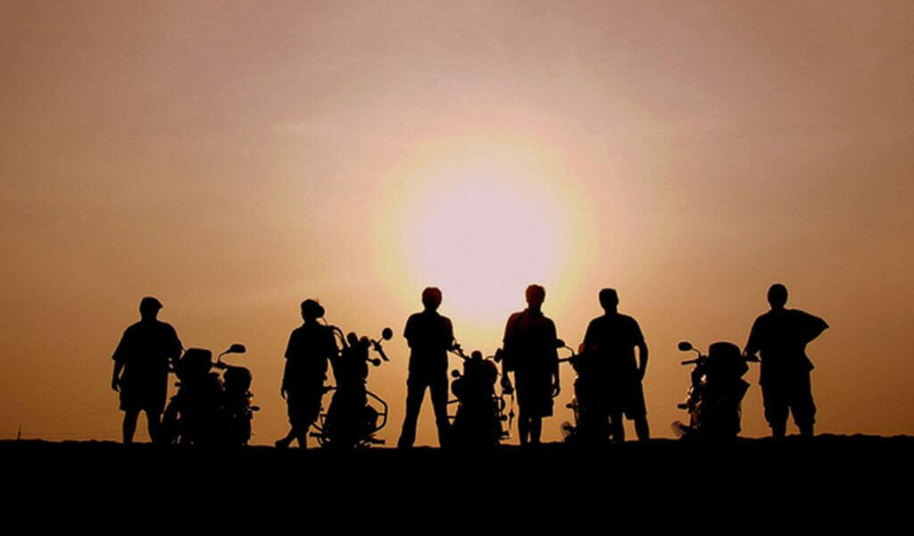 Silhouette of a group of riders with their motorcycles against the sunset sky.