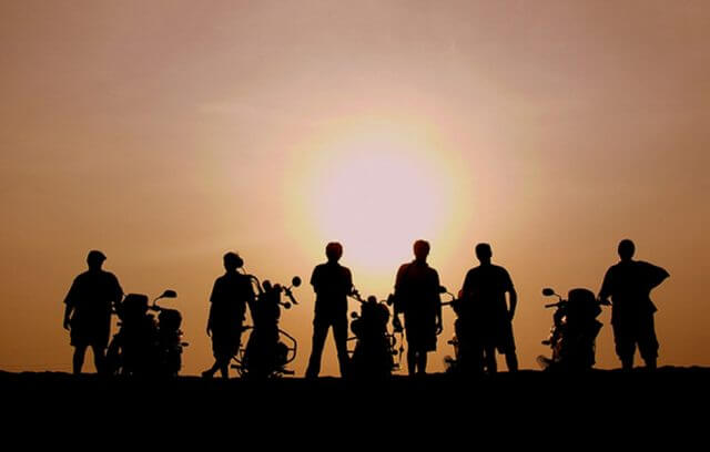 Silhouette of a group of riders with their motorcycles against the sunset sky.