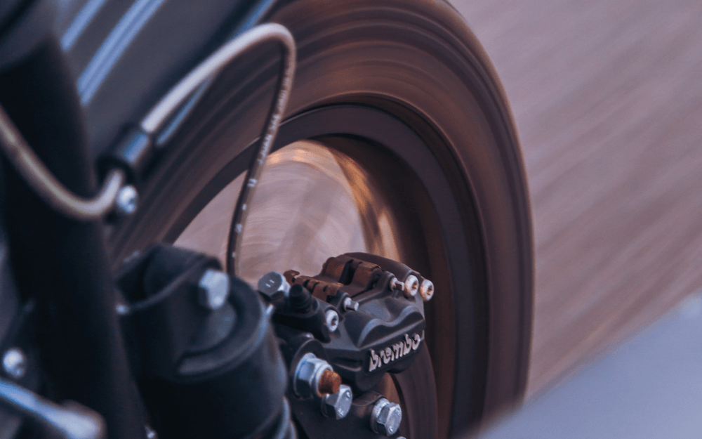 Close-up of a motorcycle's spinning wheel in motion, focusing on the brake caliper