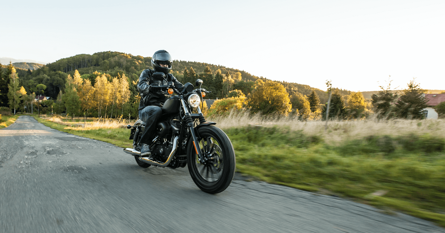 Motorcyclist in black gear enjoying a ride on a country road at dusk